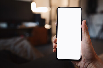 POV photo of man holding smartphone with white screen while sitting on a couch