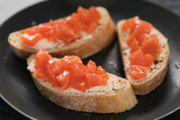 Bruschettas with salmon and cream cheese on black plate closeup