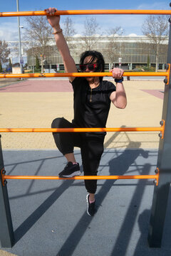 Woman exercising outdoors on parallel bars in urban environment