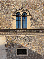 Palazzo corvaja bifora window and stone wall in taormina