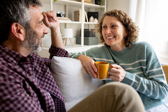 Happy mature couple relaxing on sofa talking and smiling