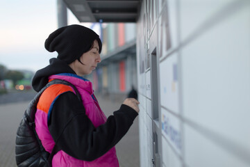 Student retrieving online order at locker, focused expression, beanie and backpack, tapping touchscreen, campus platform backdrop, youthful streetstyle and efficient pickup moment