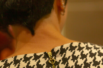 Close up back neck houndstooth detail, female model seen from rear with short dark hair, small stud...