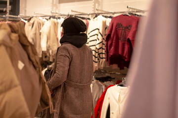 Buyer choosing jacket, Person thoughtfully selecting clothing as thoughtful gift at store, Shoppers carefully inspect and evaluate coat options while considering perfect gift possibility