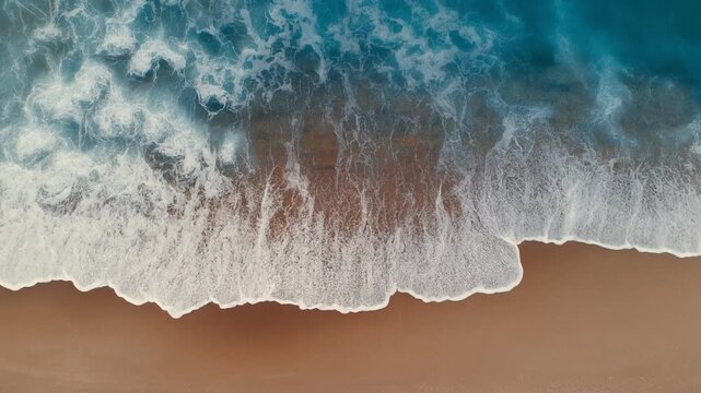Cinematic aerial drone shot of turquoise ocean waves crashing on sandy beach, peaceful tropical nature.