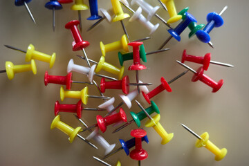 Collection of push pins in various colors scattered on a flat surface