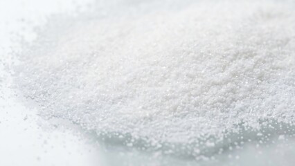 Close up view of a pile of fine white granular substance possibly salt or sugar on a white surface