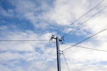 Utility pole with power lines against cloudy sky in daylight