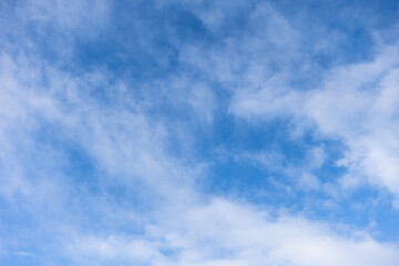 Wispy cirrus clouds in blue sky during calm daytime weather