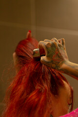 caucasian woman red hair being brushed by tattooed stylist's hand, close-up of glossy strands under warm