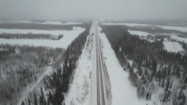 An aerial, eye-level shot flying forward along a snow-covered stretch of the remote Alaska Highway between Whitehorse and Haines Junction, Yukon, Canada