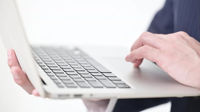 Video of a man using a computer to type inquiries or browse FAQs while operating the trackpad Close-up of upper body and hands only,without face