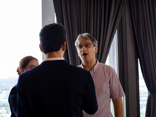 Business professionals engaged in conversation during corporate event, with one man actively speaking, highlighting leadership, communication, and idea sharing in workplace culture