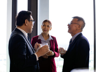 Three business professionals having a friendly conversation at a corporate event, showing connection, communication, and professional networking