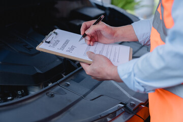 Auto technician holding a clipboard and reviewing vehicle insurance policy. Concept of vehicle insurance, car service, maintenance check, safety inspection, and automotive documentation.