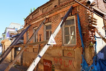 An old brick house in the old town of Tbilisi, the facade of the house is supported by metal structures.