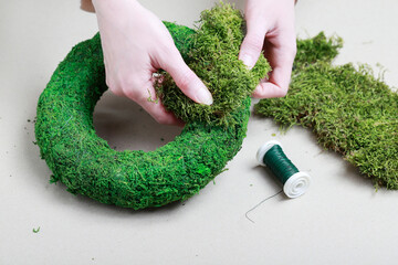 Florist at work: woman shows how to make classic moss wreath. Step by step, tutorial.