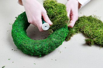 Florist at work: woman shows how to make classic moss wreath. Step by step, tutorial.