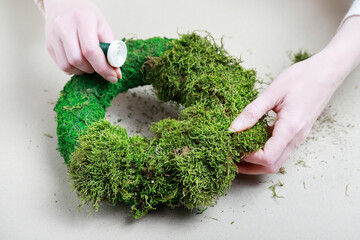 Florist at work: woman shows how to make classic moss wreath. Step by step, tutorial.