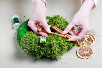 Florist at work: woman shows how to make classic moss wreath. Step by step, tutorial.