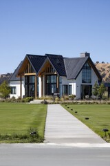Modern house stands in open landscape with clear sky in daytime, showcasing design and architecture in a suburban setting, walking path leading to entrance