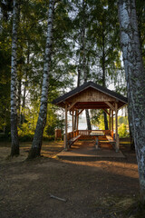 A picturesque lakeside pavilion built from natural wood, surrounded by tall trees and soft evening light. This peaceful forest retreat evokes simplicity, sustainability, and a connection to nature.