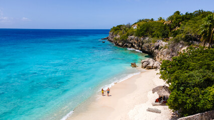 Fototapeta premium Experience the beauty of Playa Kalki Beach in Westpunt, Curaçao. Sunbathers enjoy the soft sand, while turquoise waves gently lap the shore. A perfect tropical escape for relaxation and adventure.
