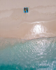 Fototapeta premium Visitors relax on soft white sands of Klein Curacao, enjoying the crystal-clear waters and warm sunshine. A perfect setting for a tropical holiday filled with bliss and tranquility.