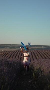 Girl toy airplane lavender field, happy child running playing at sunset light. Vertical video