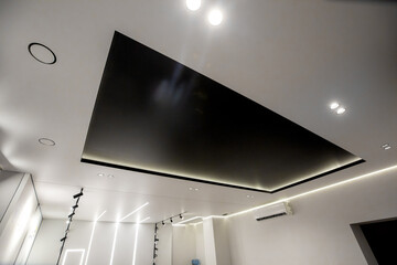 A minimalist interior photo of a ceiling with a contrasting black niche and modern LED lighting in a black and white style.
