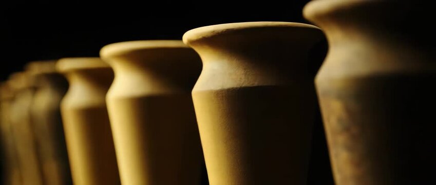 Row of Aged Rustic Textured Pottery Vases in Dark Background