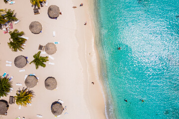 Cas Abao Beach in Curacao stunning turquoise water and soft sandy shores. Visitors relax under palm...