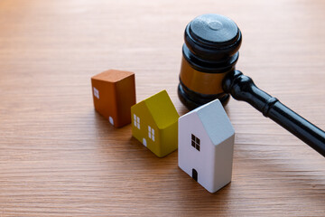 Wooden judge gavel beside miniature houses on a table. Real estate law, property auction, foreclosure, housing dispute concept