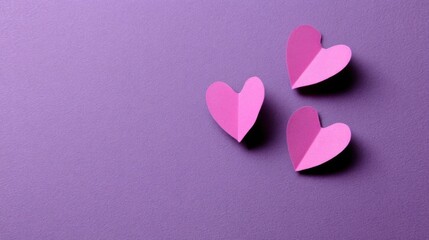 Four pink heart shapes arranged together on purple paper material, two larger hearts flanking one smaller heart,