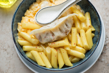 Korean tteokbokki or garaetteok served with steamed dumpling and egg in a dark-blue bowl, middle closeup, horizontal shot