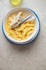 Bowl of cheesy tteokbokki or rice cakes with steamed egg and dumpling, vertical shot on a beige stone background with space, above view