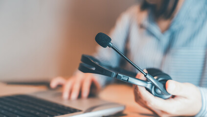 Woman holding headset while working on laptop,symbolizing customer service assistance,technical support,online communication,telemarketing,call center environment in modern business,efficient online 