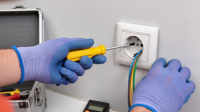 electrician fixing electrical outlet - Powered by Adobe