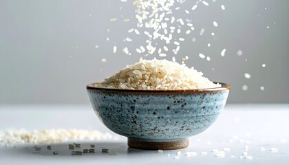 White rice grains falling into a ceramic bowl on white background
