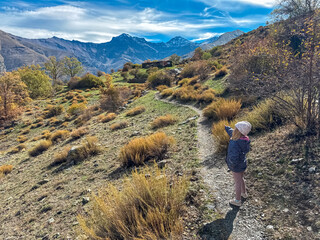 A young girl points at the view while standing on the Vereda de la Estrella trail facing the majestic Mulhacen and Alcazaba peaks in the sunny Sierra Nevada National Park, Andalusia, Spain.