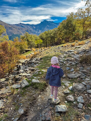 A young girl in a striped jacket hikes along the rocky Verada de la Estrella trail towards the Mulhacen and Alcazaba peaks in the vast Sierra Nevada National Park, Andalusia, Southern Spain.