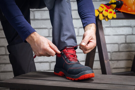 Close-up of worker putting on shoes for work. Safety work.