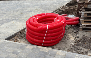 Workers placed red plastic pipes for drainage near new pavement in a construction area
