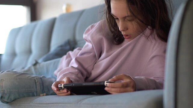 A child holding a game controller while playing a video game. Close-up. After-school entertainment and relaxation. A child playing a video game.