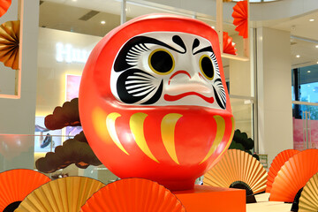 新年の抱負や必勝祈願を象徴する大きなダルマのオブジェ、松と扇子をあしらった和風の正月ディスプレイ素材