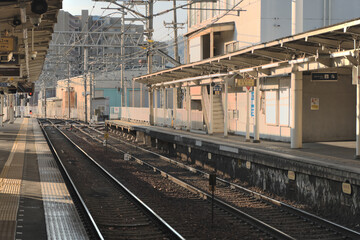 Fototapeta premium 青空の下に広がる日本の地方都市の鉄道駅のホームと架線、静かな昼下がりの駅構内の風景素材