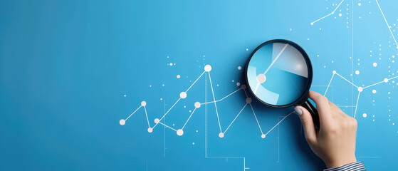 Hand holding magnifying glass highlighting rising chart on blue background, symbolizing data analysis, financial growth, performance review, research insight and strategic decision making.