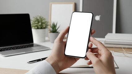 Person Holding Smartphone with Blank White Screen Over Blurred Office Desk with Laptop and Plants, Mobile App Mockup