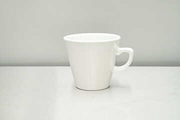 Obraz premium A small white porcelain cup on a stainless steel surface