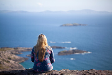 Blonde woman looking at a coastal landscape in Ireland